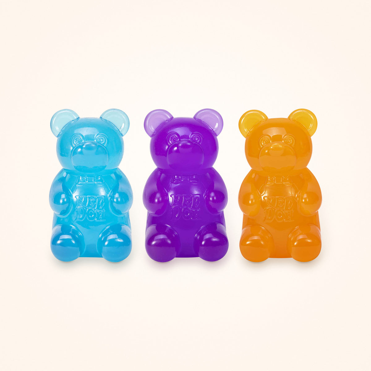 Squishy Stocking Stuffer: three NeeDoh Gummy Bears in blue, purple and orange, shown to scale on a cream background