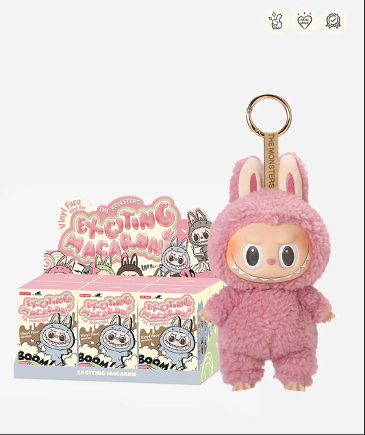 Labubu Exciting Macaron display case of sealed boxes next to a pink Lychee Berry pendant; small badge icons top right