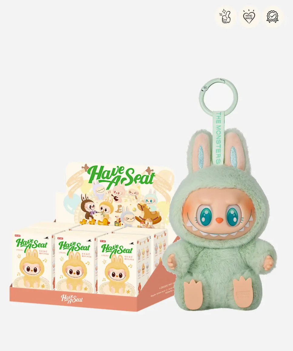 Labubu Have a Seat display case of sealed boxes next to the mint green Ququ figure; small badge icons top right