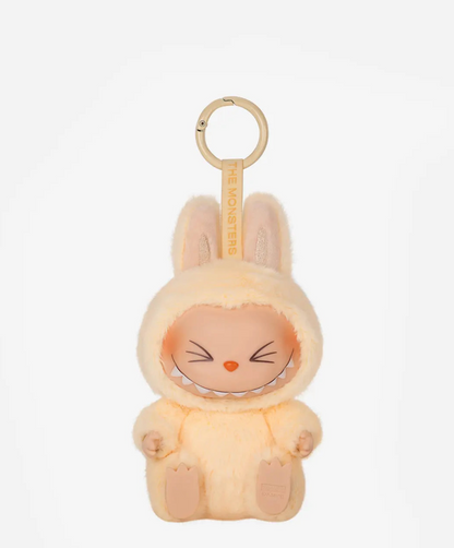 Sisi, the pale yellow Labubu Have a Seat figure with squinting eyes, on a gold keyring