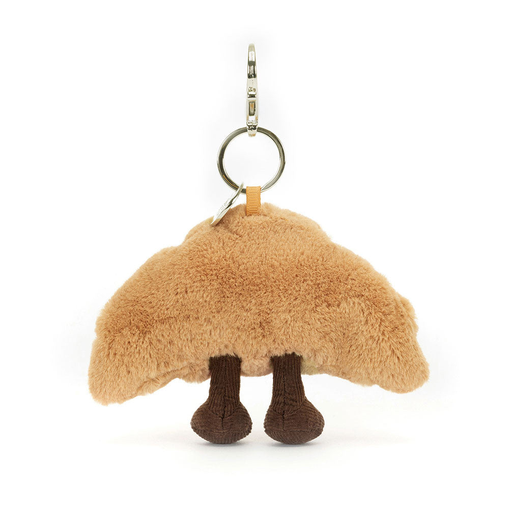 Back of the Jellycat Amuseables Croissant plush bag charm, with brown cord boots and the keyring on top