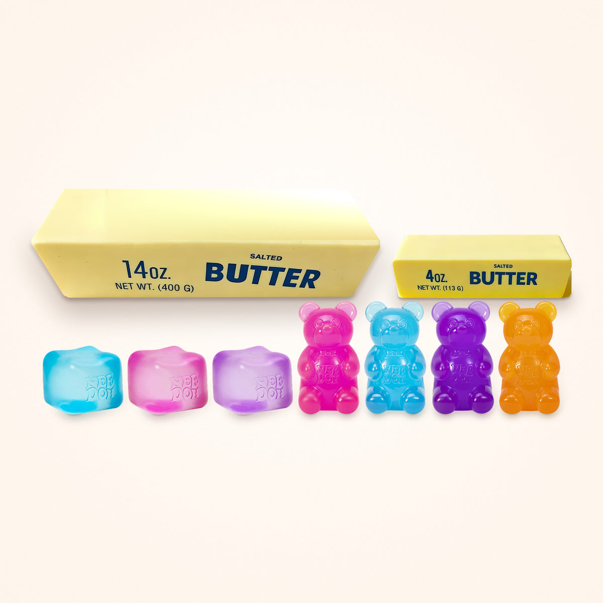 Squishy Gift Box Everything: all three NeeDoh Nice Cube colors and all four NeeDoh Gummy Bear colors in front of a Giant and a Mini Butter Squishy, shown to scale on a cream background