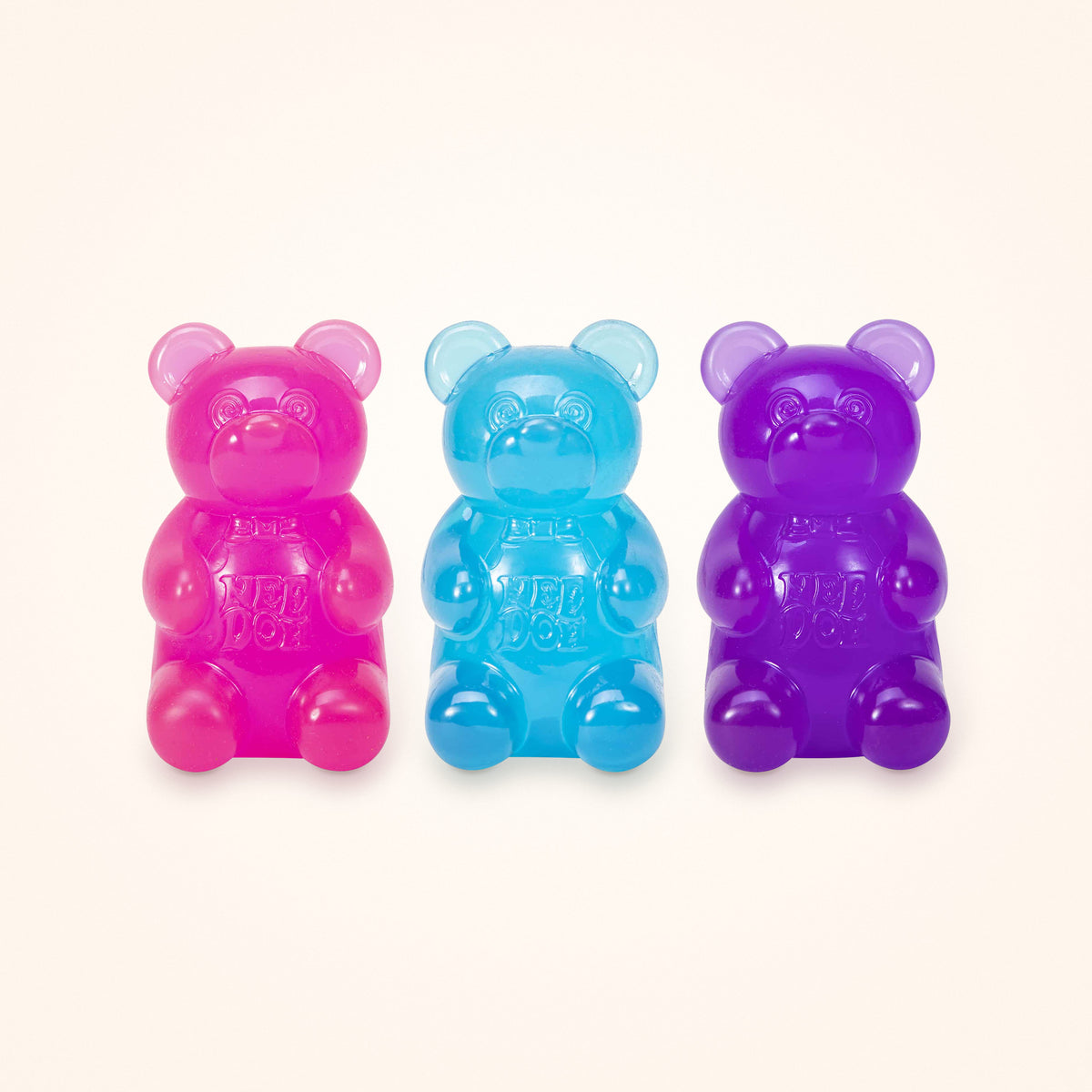 Squishy Stocking Stuffer: three NeeDoh Gummy Bears in pink, blue and purple, shown to scale on a cream background