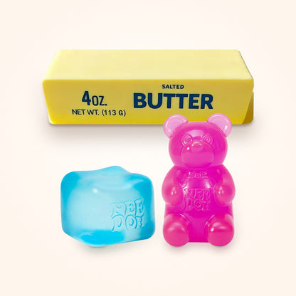 Squishy Gift Box Trio: a blue NeeDoh Nice Cube and a pink NeeDoh Gummy Bear in front of a Mini Butter Squishy, shown to scale on a cream background