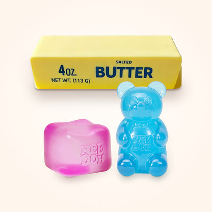 Squishy Gift Box Trio: a pink NeeDoh Nice Cube and a blue NeeDoh Gummy Bear in front of a Mini Butter Squishy, shown to scale on a cream background
