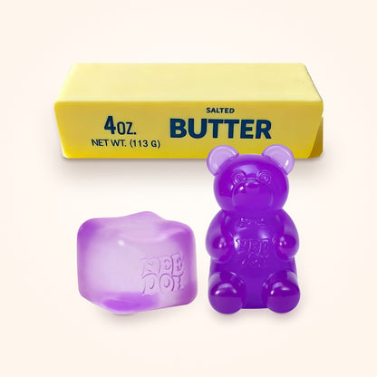 Squishy Gift Box Trio: a purple NeeDoh Nice Cube and a purple NeeDoh Gummy Bear in front of a Mini Butter Squishy, shown to scale on a cream background